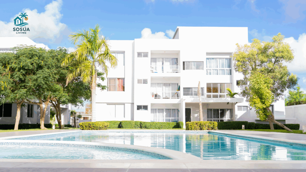 Three-story modern apartment building with large swimming pool and palm trees in Sosúa